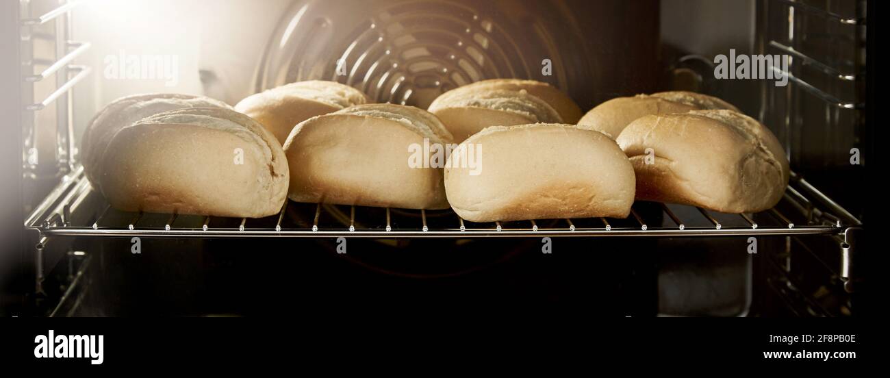 Panini caldi appena sfornati con crosta croccante su metallo griglia in forno da forno Foto Stock