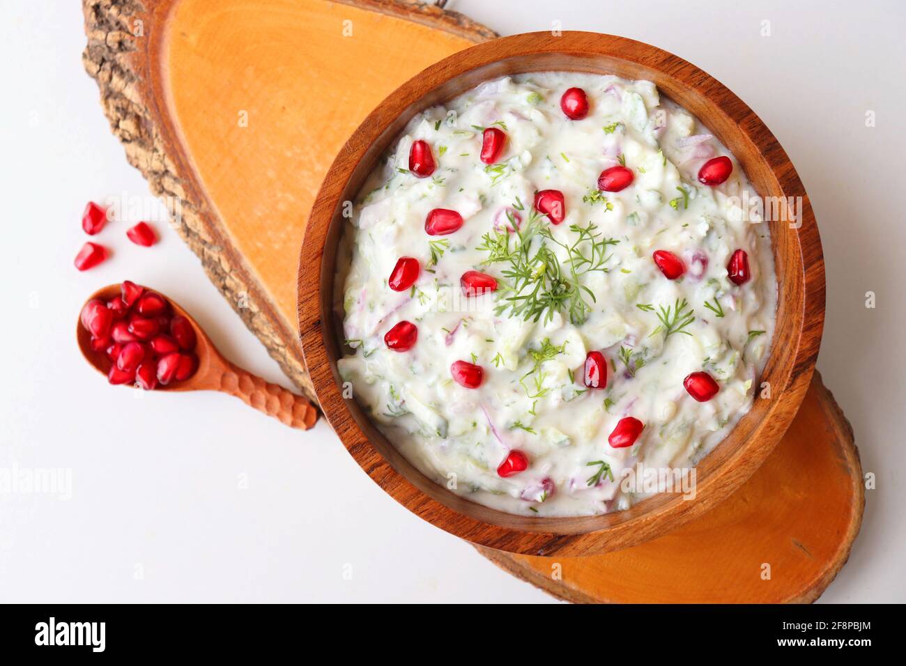 Melograno e cetriolo Raita. Salsa fresca indiana o condimento chiamato Raita. Yogurt mescolato con cetriolo grattugiato, cipolle, melograno e spezie. Foto Stock