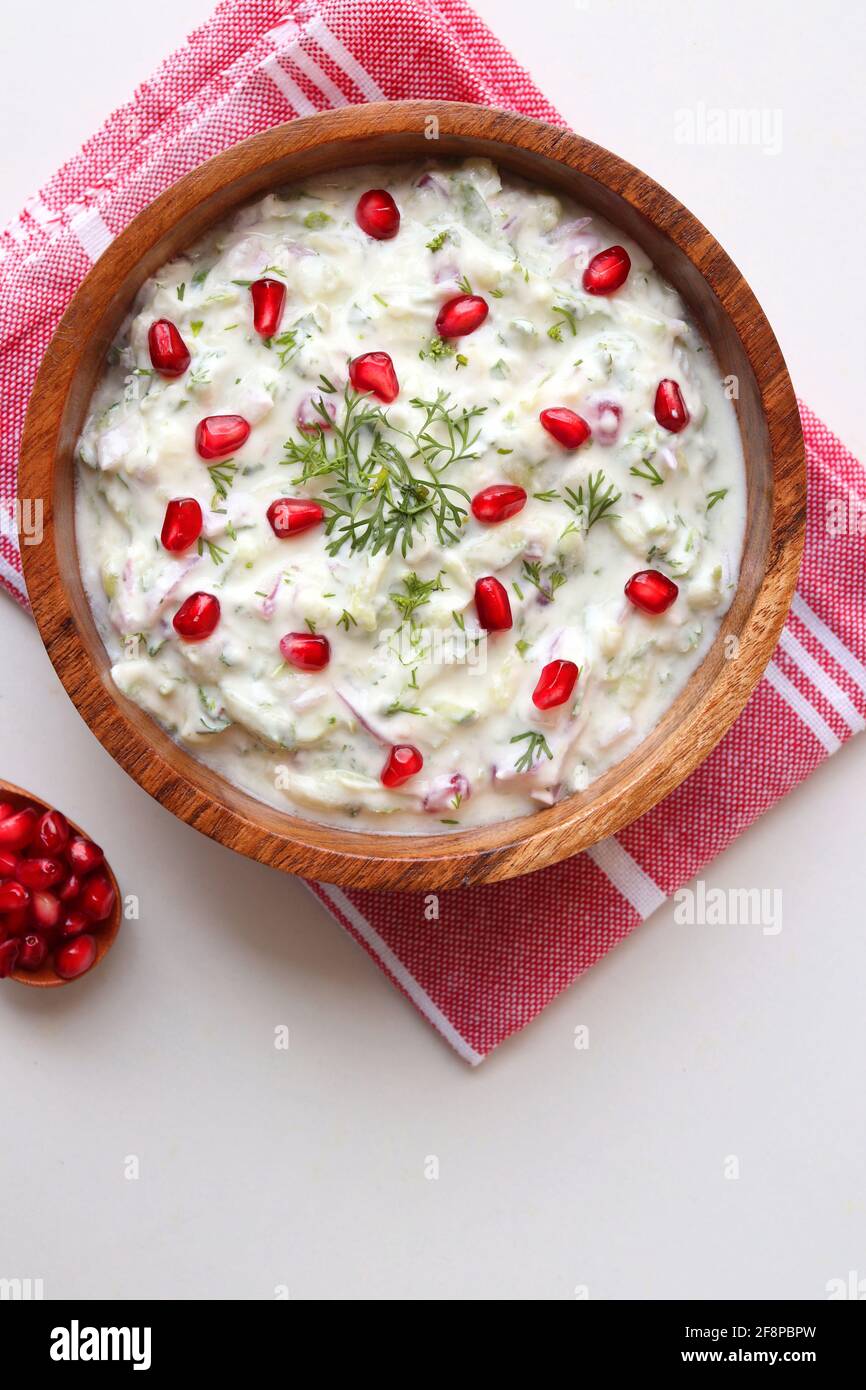Melograno e cetriolo Raita. Salsa fresca indiana o condimento chiamato Raita. Yogurt mescolato con cetriolo grattugiato, cipolle, melograno e spezie. Foto Stock