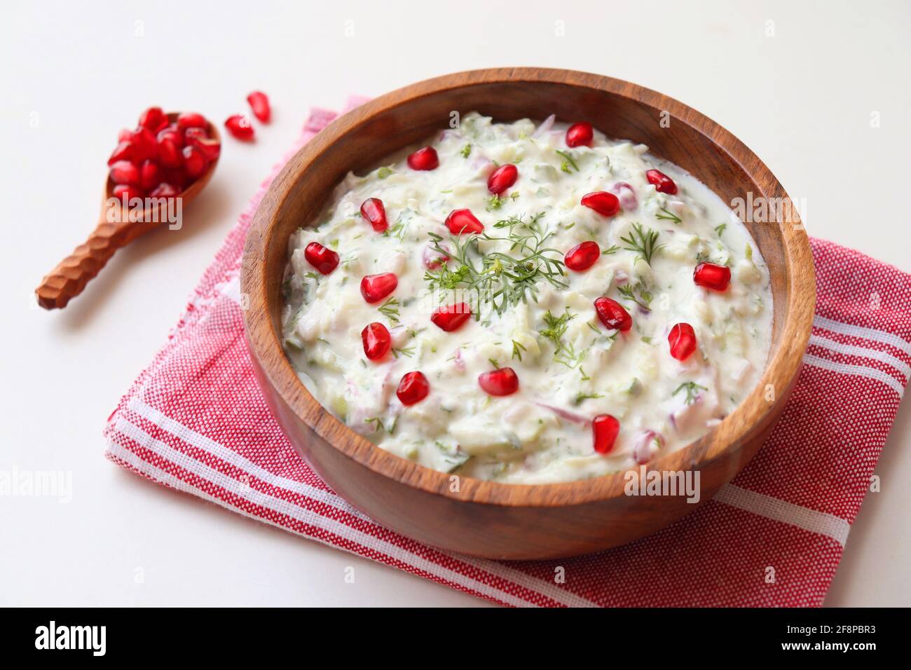 Melograno e cetriolo Raita. Salsa fresca indiana o condimento chiamato Raita. Yogurt mescolato con cetriolo grattugiato, cipolle, melograno e spezie. Foto Stock