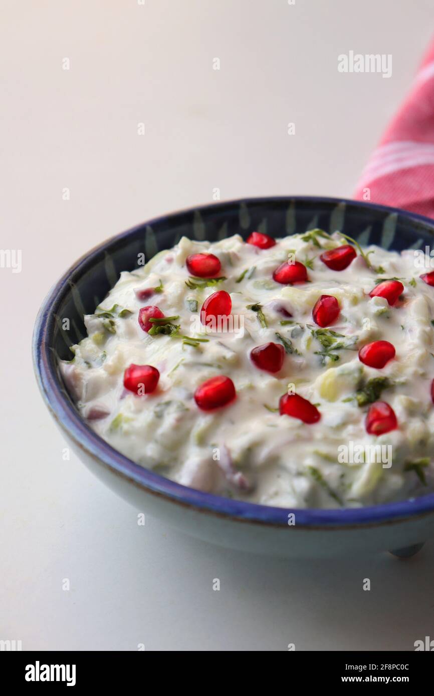 Melograno e cetriolo Raita. Salsa fresca indiana o condimento chiamato Raita. Yogurt mescolato con cetriolo grattugiato, cipolle, melograno e spezie. Foto Stock