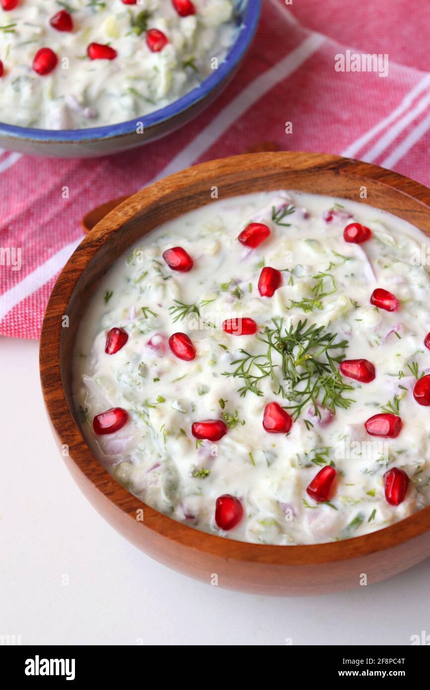 Melograno e cetriolo Raita. Salsa fresca indiana o condimento chiamato Raita. Yogurt mescolato con cetriolo grattugiato, cipolle, melograno e spezie. Foto Stock