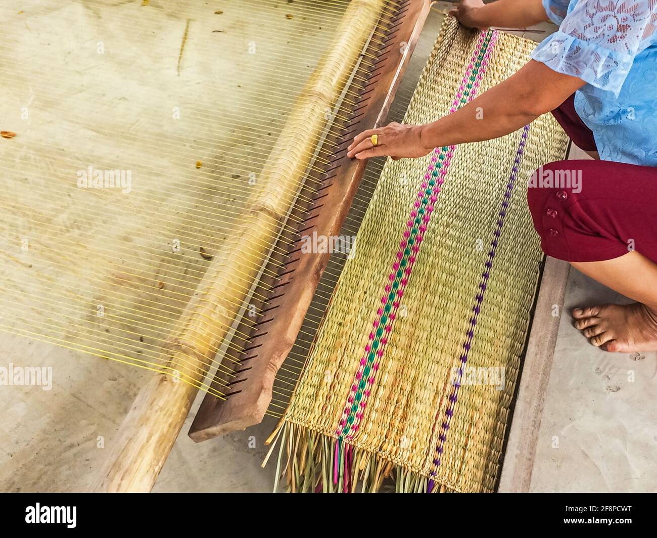 Le mani delle donne stuoie tessute tradizionalmente sono prodotti fatti a mano nella campagna della Thailandia. Foto Stock