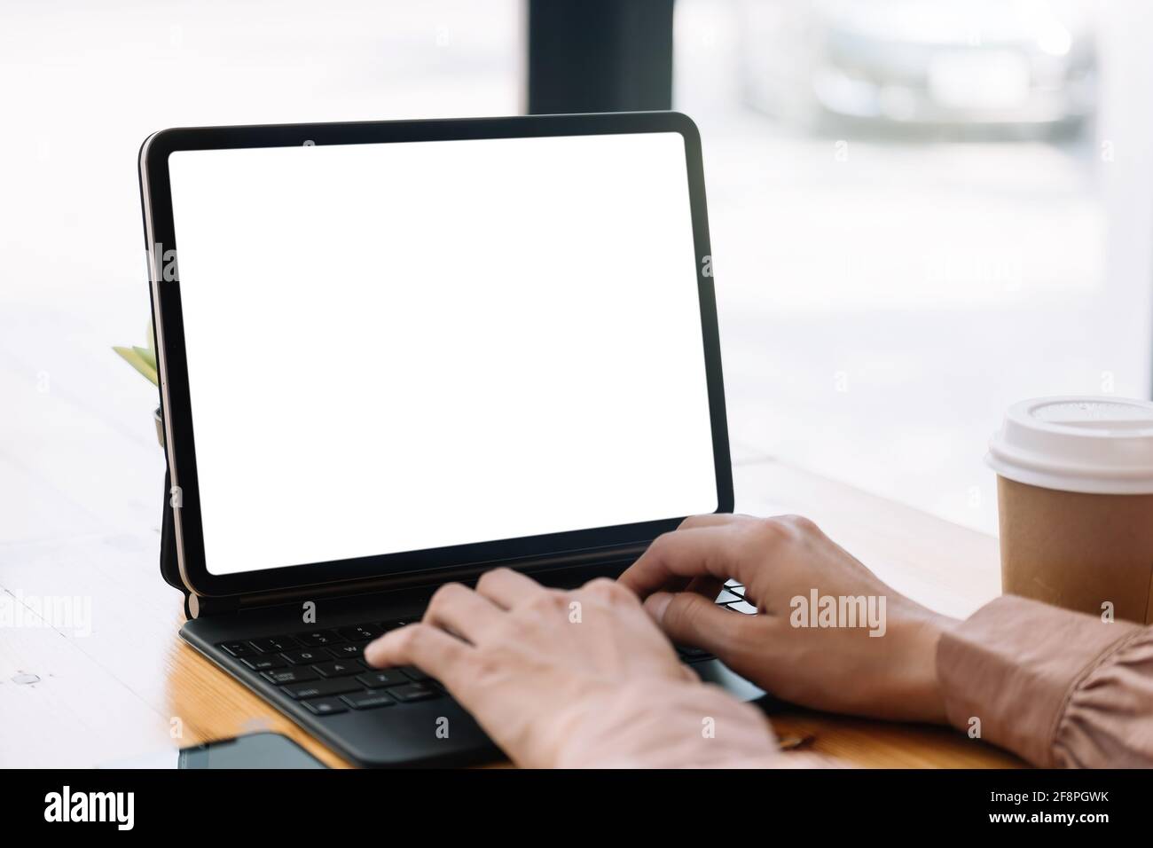 Primo piano mano di donna che scrive su smart tablet con schermata bianca vuota sul tavolo Foto Stock