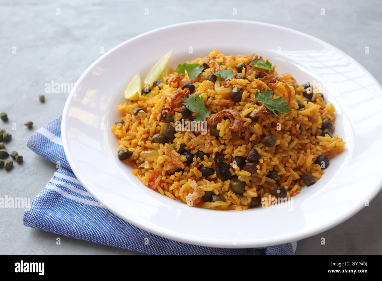 Cucina indiana - ceci Biryani, chole Pulao. Guarnito con cipolla fritta, coriandolo tritato e spicchi di limone. Kala chana biryani. Copia spazio Foto Stock