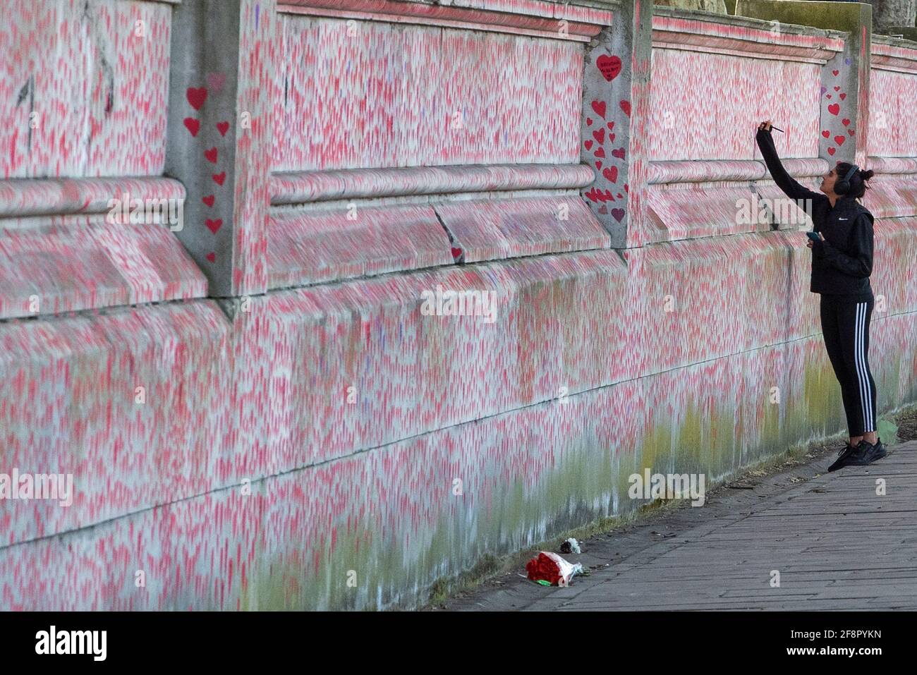 La gente cammina oltre e scrive sul muro commemorativo nazionale del Covid, a Londra il 9 aprile 2021 Foto Stock