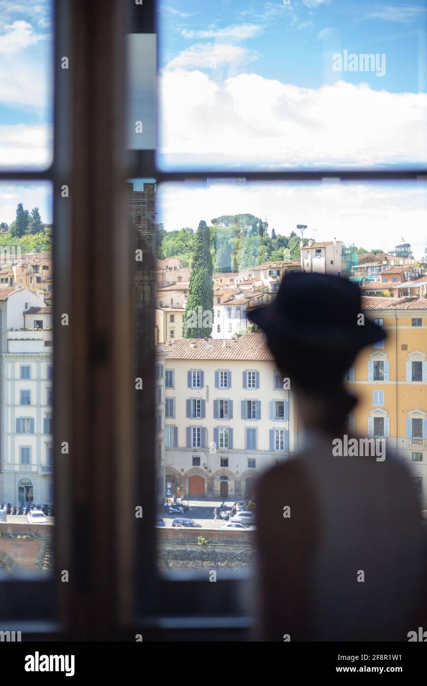 Una donna turistica guarda le strade di Firenze dall'interno della Galleria degli Uffizi, Italia Foto Stock