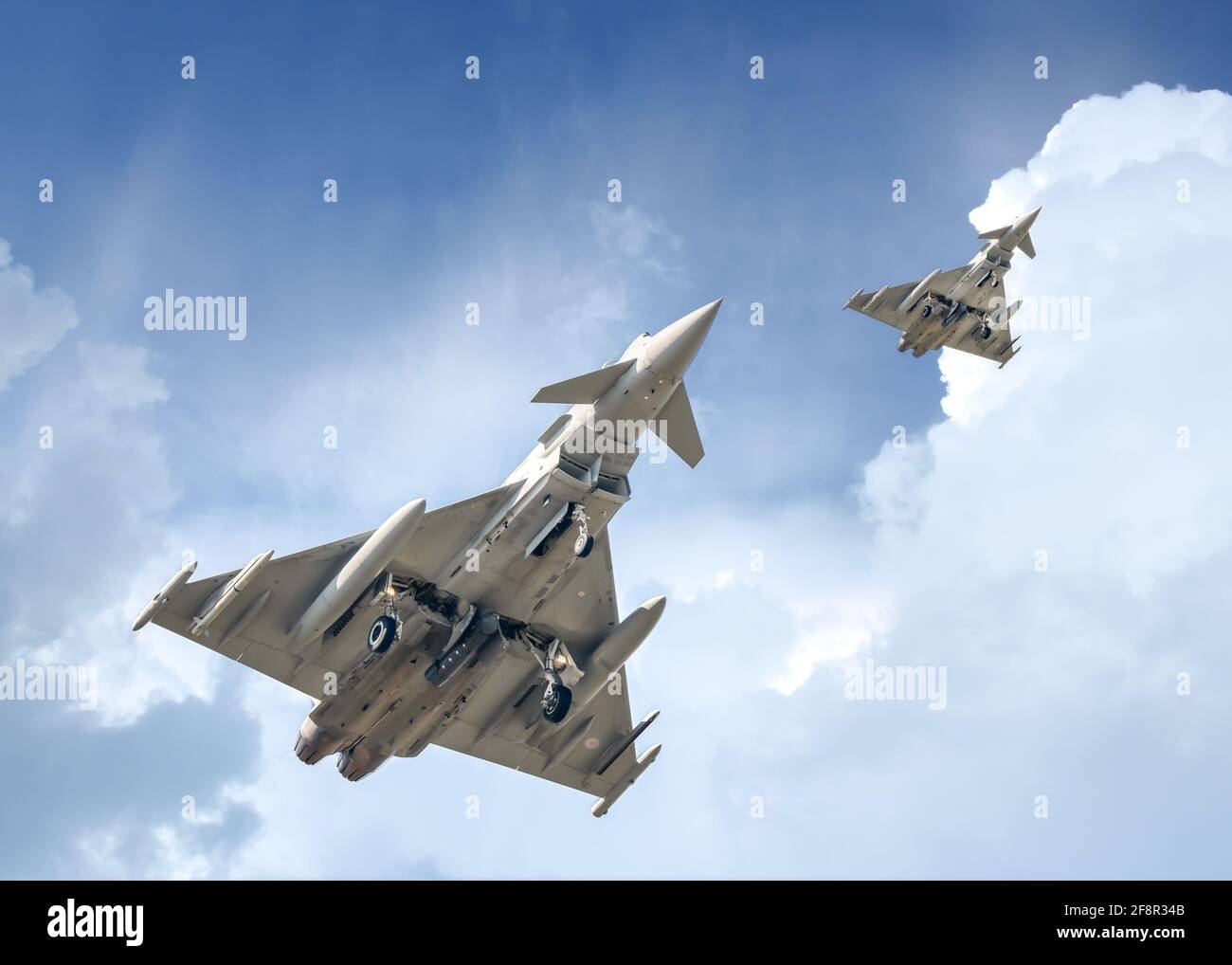 Due jet Typhoon Eurofighter che volano sul centro città con missili in missione. Moderni aerei da combattimento in formazione con incredibile drammatico Foto Stock