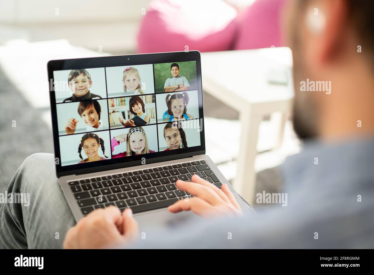 Insegnante di sesso maschile che ha una conferenza online con i bambini della scuola che lavorano a. casa Foto Stock