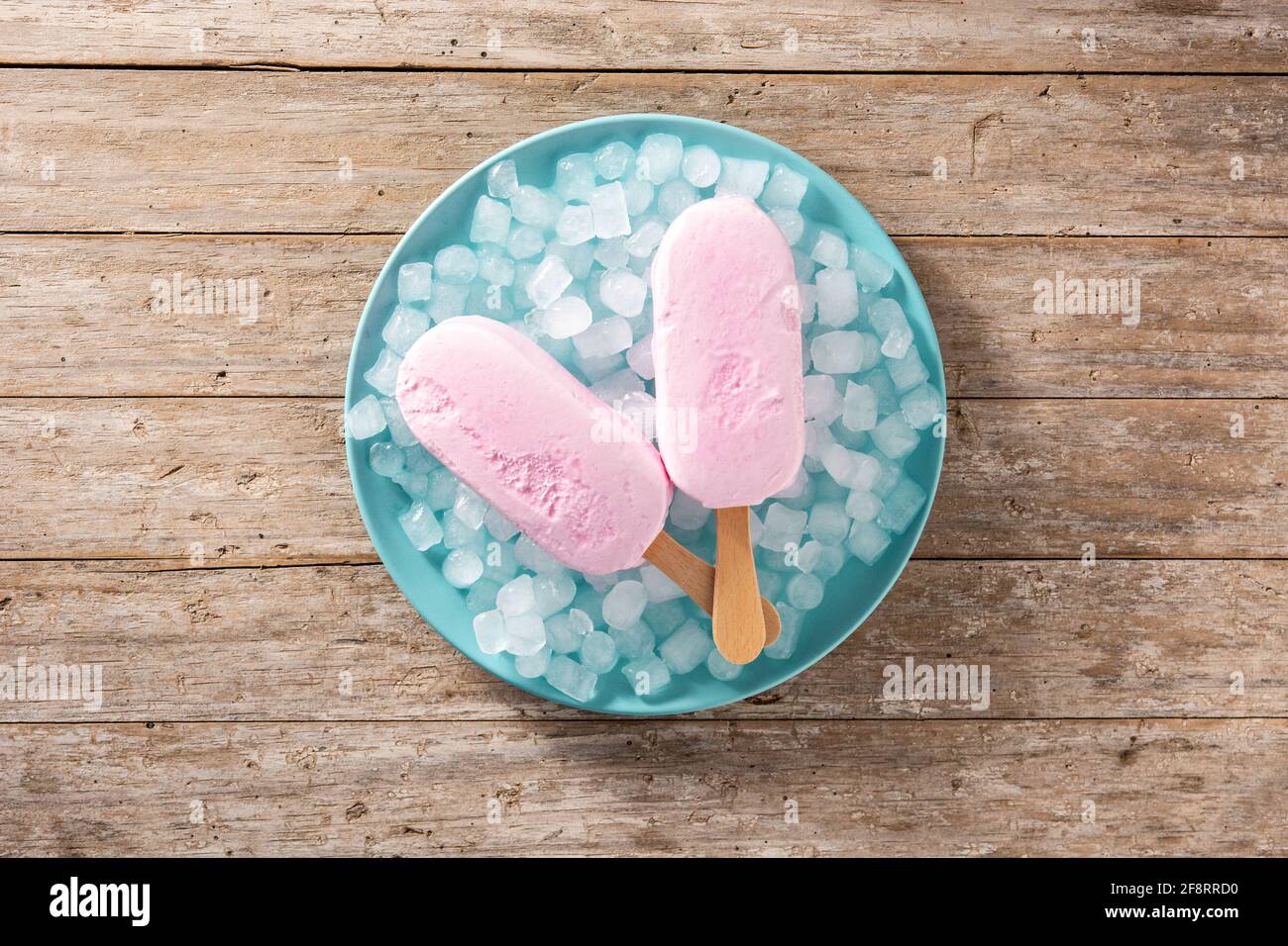 Popsicle di fragole e ghiaccio tritato su piatto blu e legno tabella Foto Stock