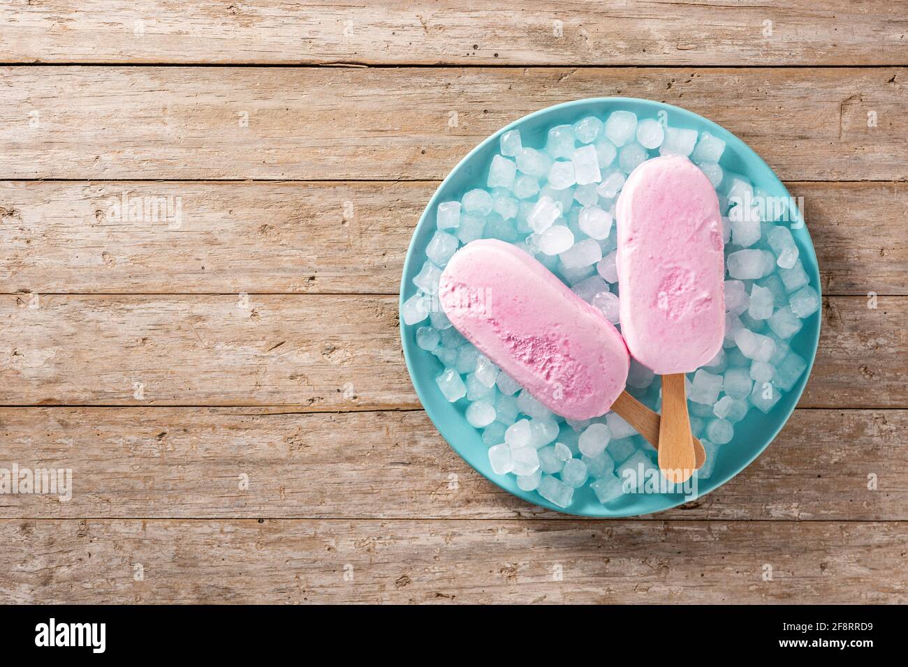 Popsicle di fragole e ghiaccio tritato su piatto blu e legno tabella Foto Stock