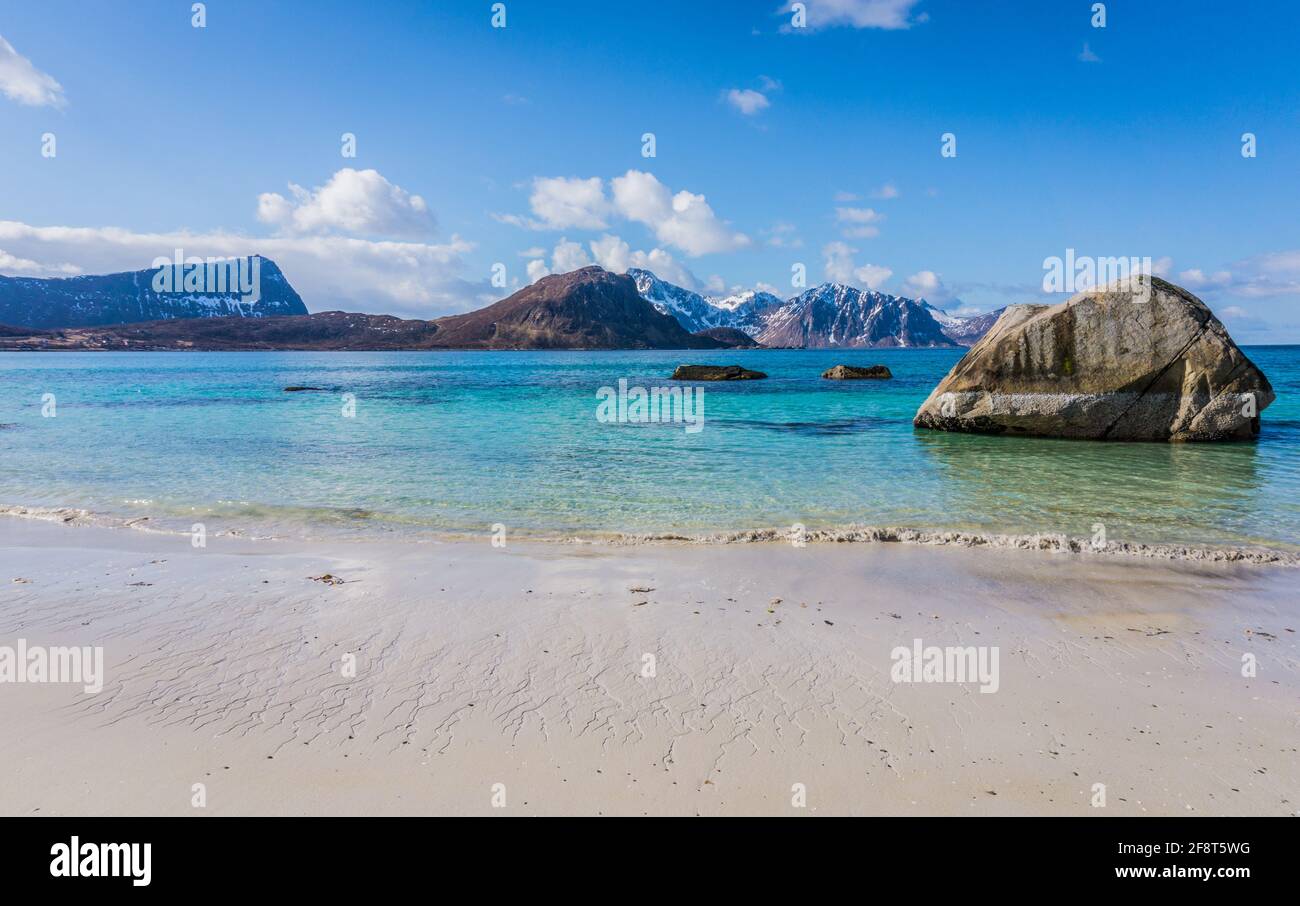 Spiaggia di Haukland o Hauklandstranda, Vestvagoy, isole Lofoten, Norvegia. Bellissima spiaggia sabbiosa con rocce, vista sulle montagne e acqua blu. Nessuna gente. Foto Stock