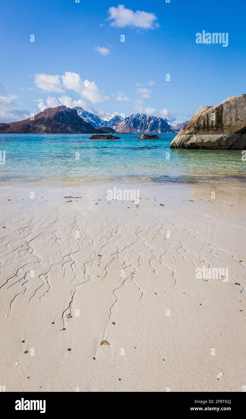 Spiaggia di Haukland o Hauklandstranda, Vestvagoy, isole Lofoten, Norvegia. Bellissima spiaggia sabbiosa con rocce, vista sulle montagne e acqua blu. Nessuna gente. Foto Stock