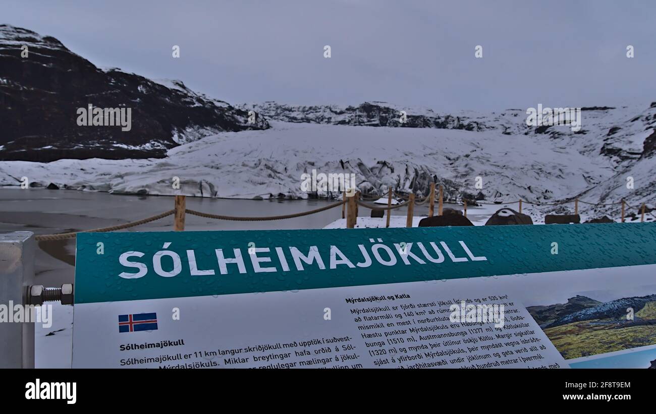 Vista del ghiacciaio Solheimajokull, parte di Mýrdalsjökull, dal punto di vista con cartello informativo di fronte il giorno nuvoloso in stagione invernale. Mettere a fuoco sul segno. Foto Stock