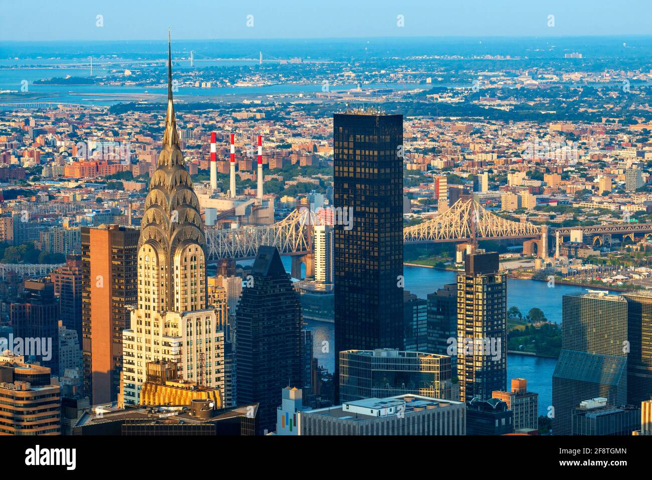 La parte superiore dell'edificio art deco Chrysler che illumina al tramonto. Preso dalla cima dell'Empire state Building. A colpo d'oro c'è anche il Queensboro Bridge. Foto Stock