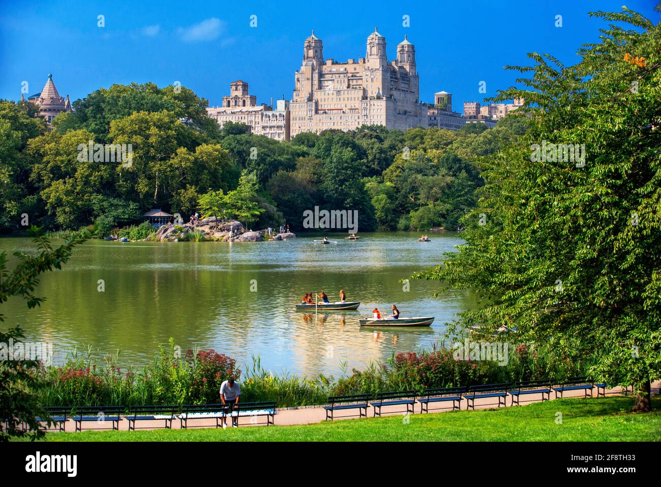 Barche a remi nel lago di Central Park, Manhattan New York, NY, USA. L'edificio Majestic sul lago artificiale Jacqueline Kennedy Onassis e Upper W Foto Stock