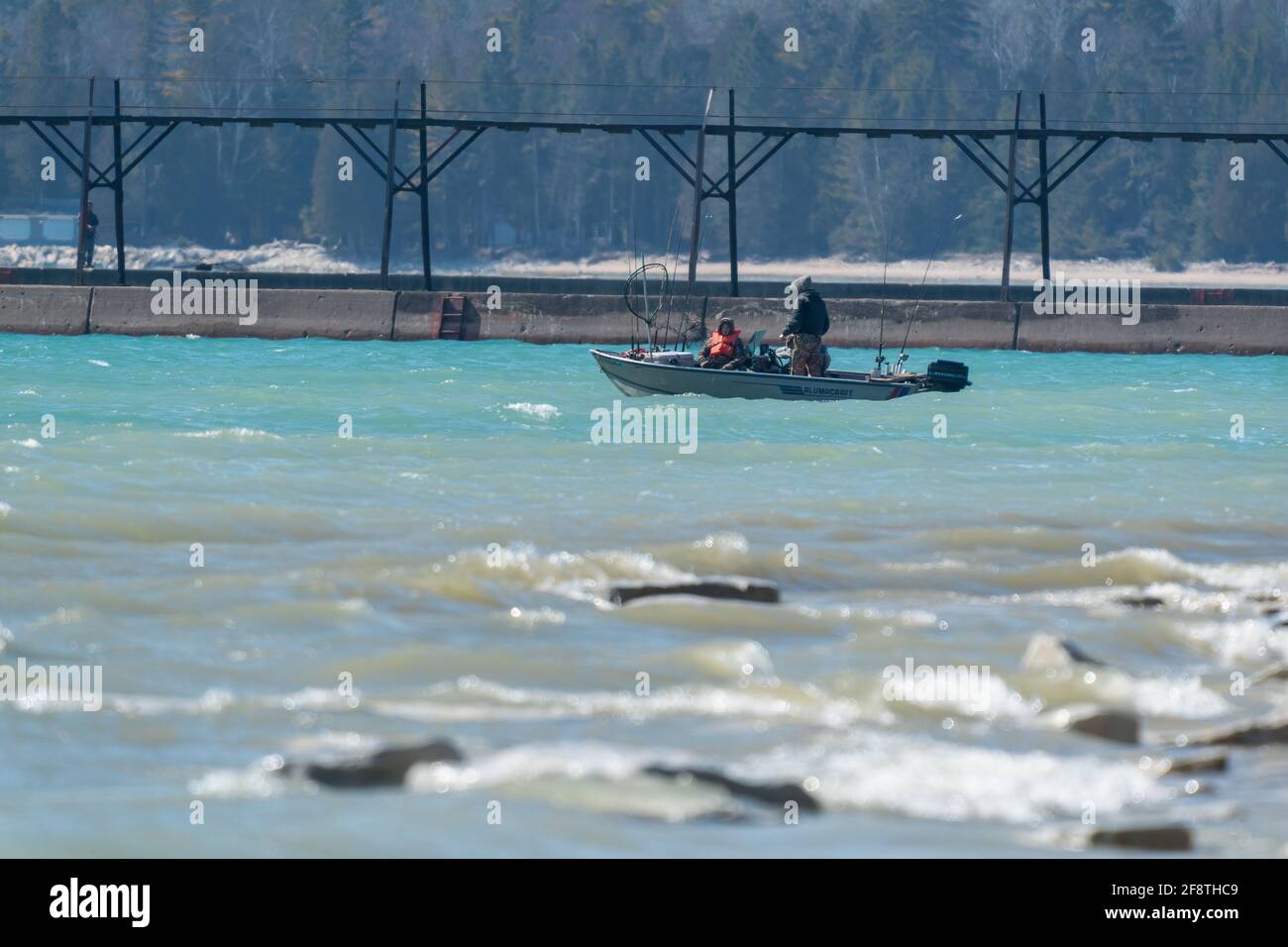 I pescatori intrepidi sfidano il vento e il freddo per alcune prime stagioni di pesca vicino al muro di rottura del canale di navigazione a Sturgeon Bay Wisconsin. Foto Stock