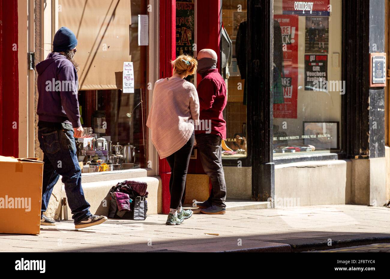 Dundee, Tayside, Scozia, Regno Unito. 15 aprile 2021. Regno Unito tempo: Una mattina soleggiata con una leggera brezza fresca attraverso la Scozia nord-orientale con temperature che raggiungono i 12°C. Il Lockdown Covid-19 si sta rilassando con la gente che fa shopping nel centro della città di Dundee, con alcuni negozi essenziali aperti per affari nella strada alta. Una coppia che sfrutta le nuove e rilassanti regole di blocco e il sole tempo di aprile che raccoglie i propri ordini di caffè dall'azienda di famiglia Braithwaite tè e caffè Negozio in Castle Street. Credit: Dundee Photographics/Alamy Live News Foto Stock