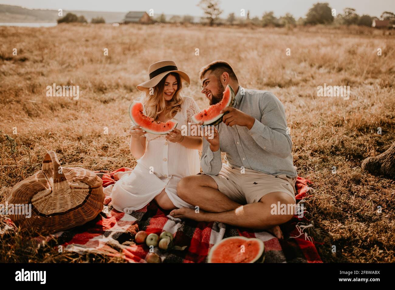 Felice famiglia europea caucasica con una donna incinta rilassarsi nella natura pic-nic mangiare frutta rosso succosa anguria ridere divertirsi Foto Stock