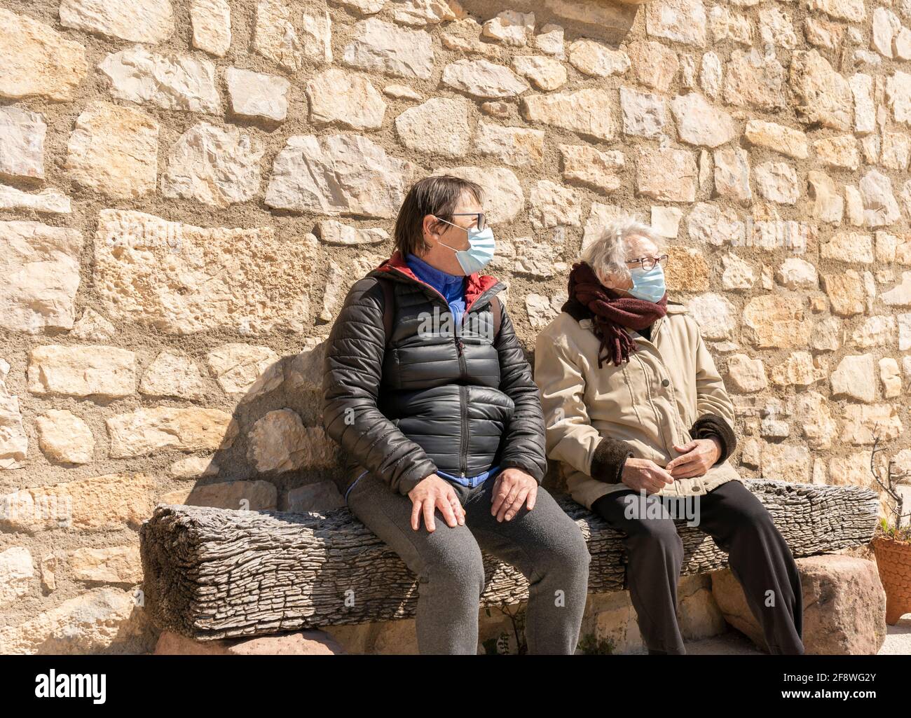 Donna anziana seduta con figlia che indossa una maschera protettiva durante la pandemia del coronavirus. Foto Stock