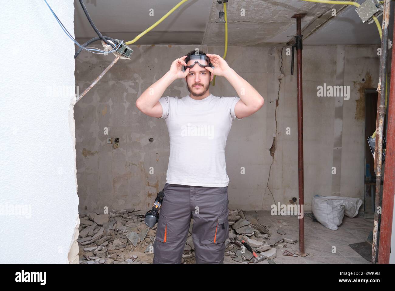 Giovane costruttore che indossa occhiali di sicurezza in un cantiere. Uomo che indossa occhiali di protezione. Foto Stock