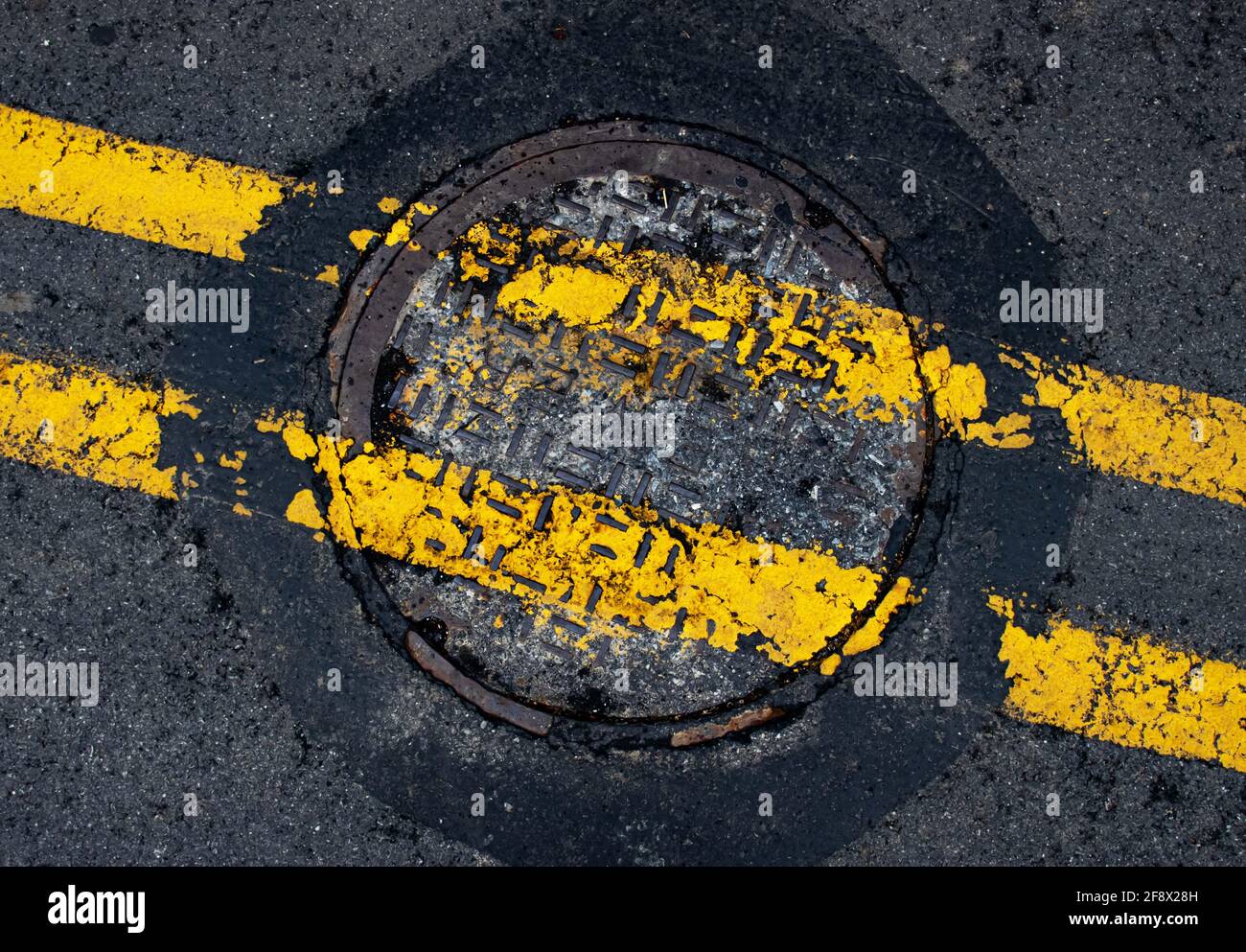 Copertura fognaria in ghisa arrugginita con Yellow Painted Road Linee divisorie nel mezzo di una Pennsylvania Street in Contea di Lancaster Foto Stock