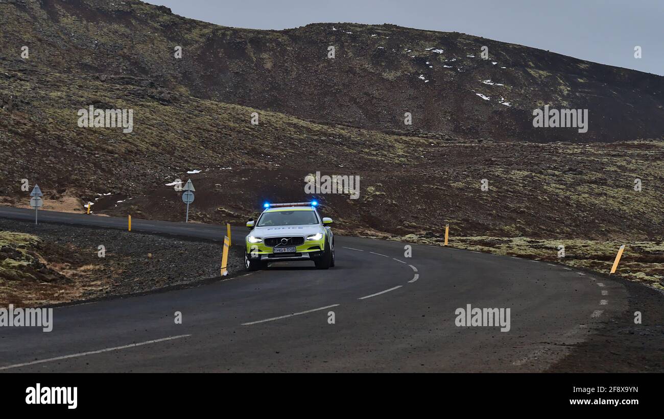 Un'unica macchina di polizia con parcheggio a luce blu lampeggiante sulla strada di campagna per regolare il traffico vicino a un'eruzione vulcanica a Fagradalsfjall. Foto Stock