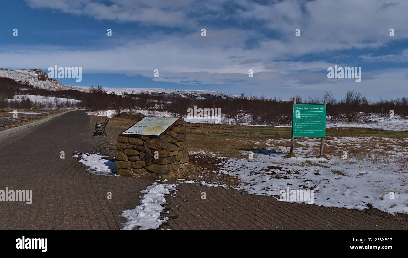 Informazioni e cartelli segnaletici all'ingresso del campo geotermico Geysir di Haukadalur, parte del Circolo d'Oro, in stagione invernale con sentiero e neve. Foto Stock