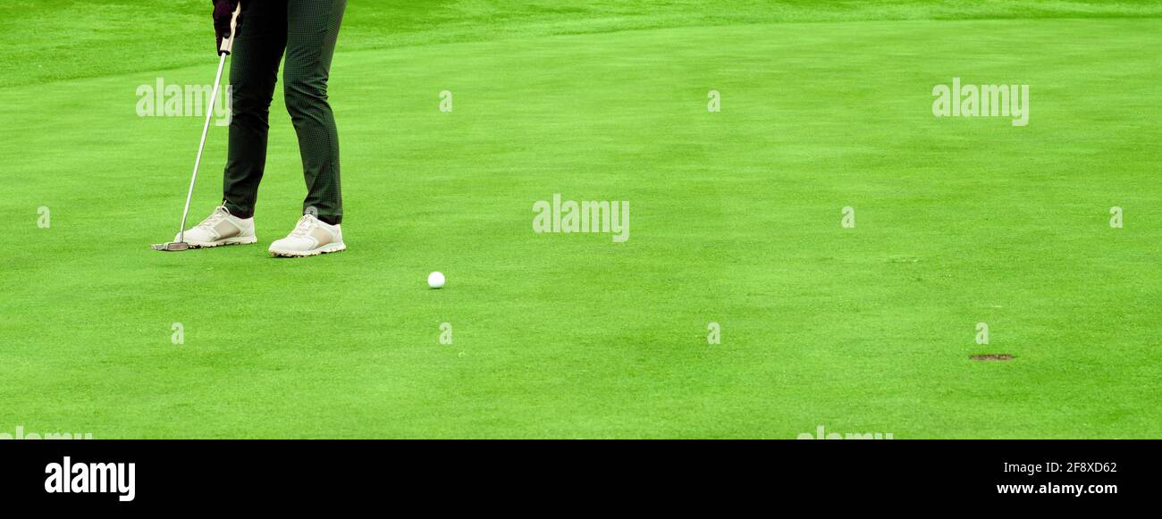 Il golfer lancia la sfera nel foro sul verde in formato banner con spazio di copia Foto Stock
