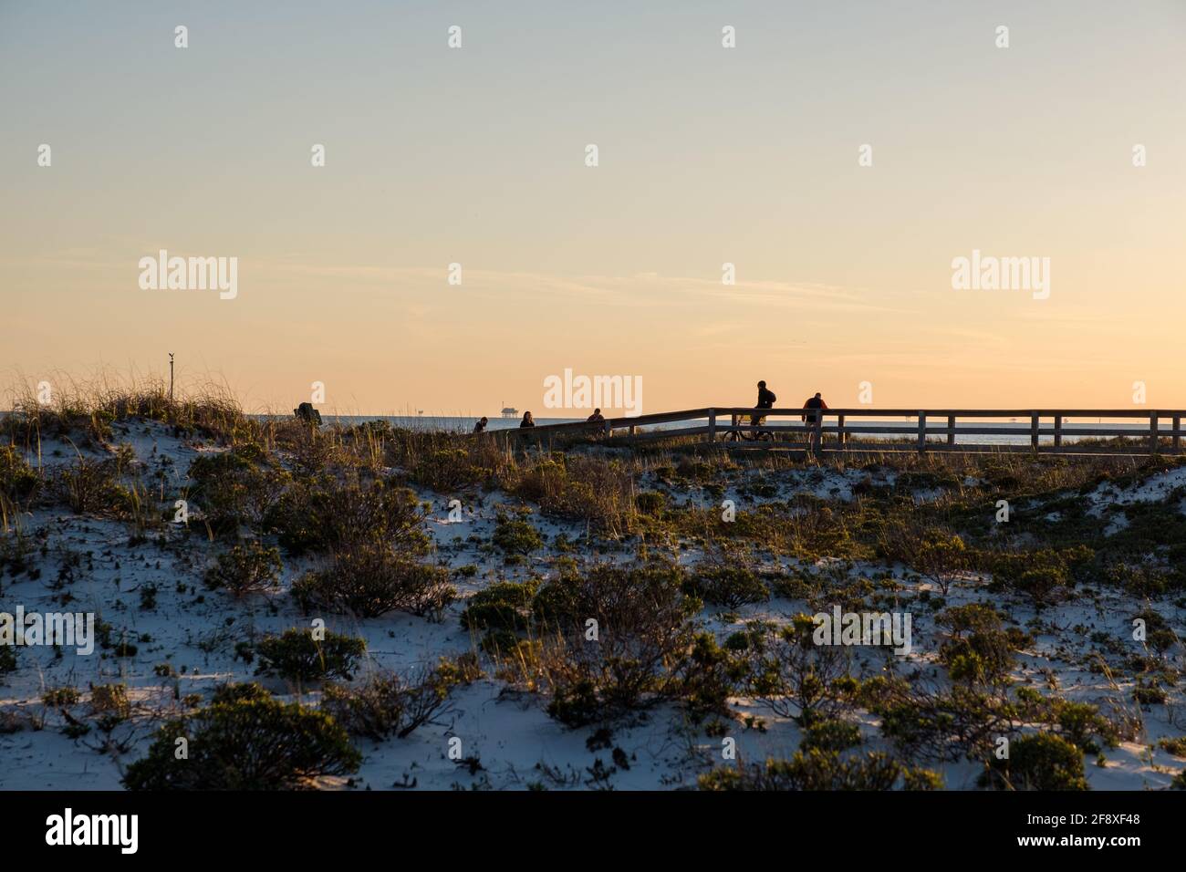 GULF SHORES, Alabama, USA - 2 APRILE 2021: Piccolo gruppo di persone dalle silhouette che camminano sul lungomare della spiaggia al tramonto Foto Stock