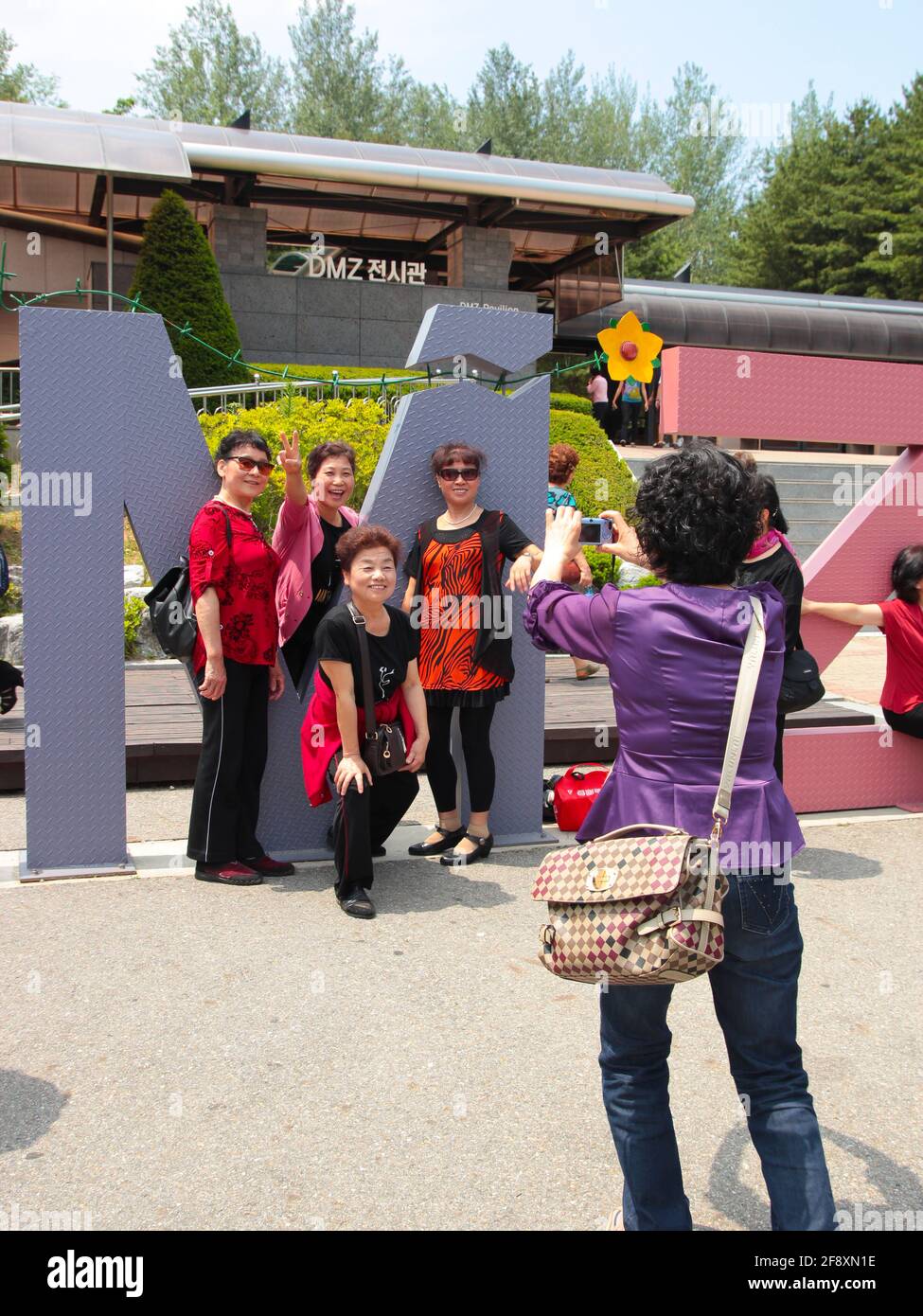 Turisti, visitatori, posa per una fotografia di fronte alle grandi lettere DMZ ritagliate presso il centro visitatori. Nella zona demilitarizzata (DMZ) vicino a Seoul, Sout Foto Stock