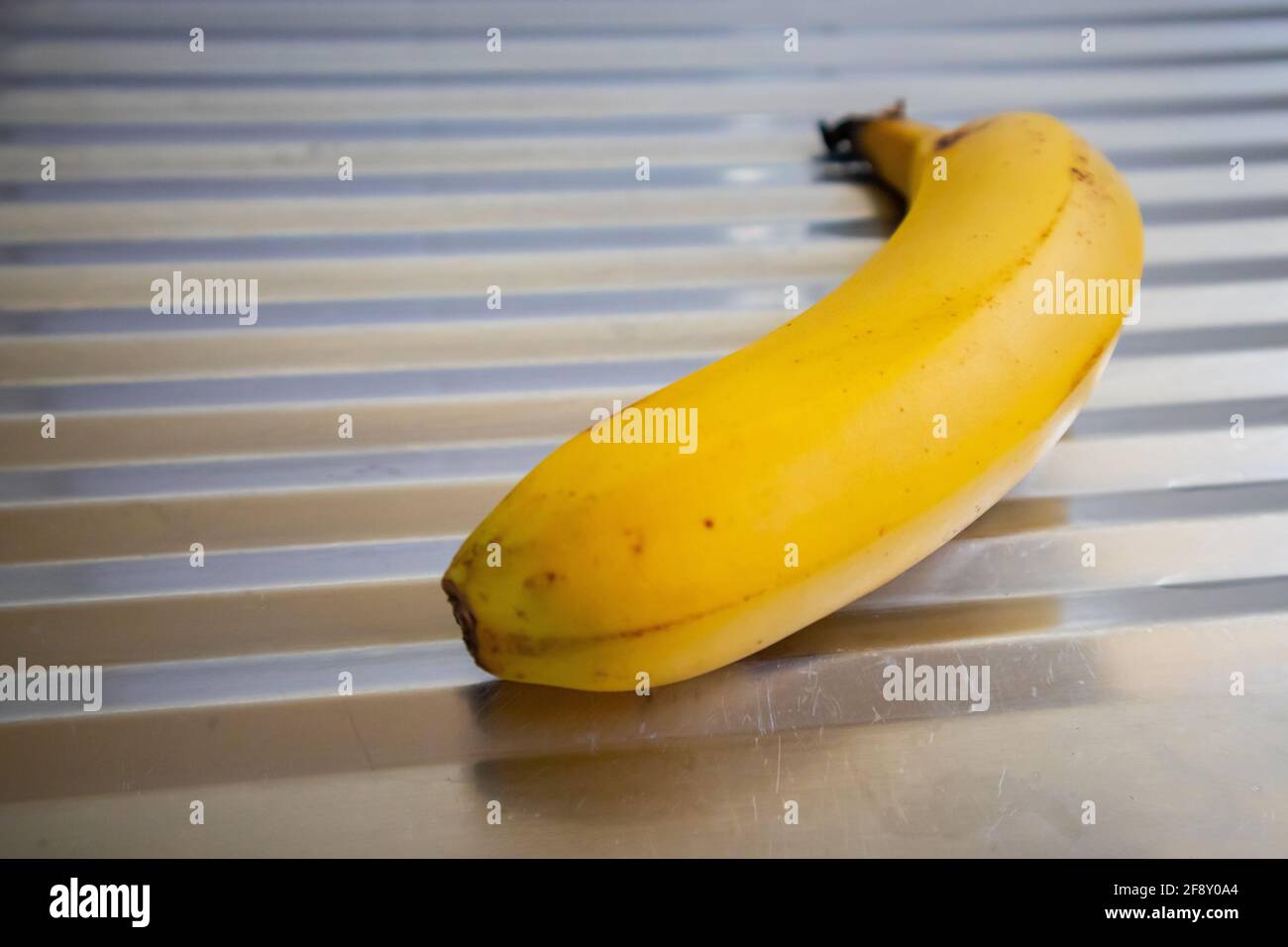 Città del Capo, Sud Africa - 06-04-2021 primo piano di una banana gialla luminosa che riposa sul lavandino della cucina. Cibo sano e concetto di casa. Foto Stock
