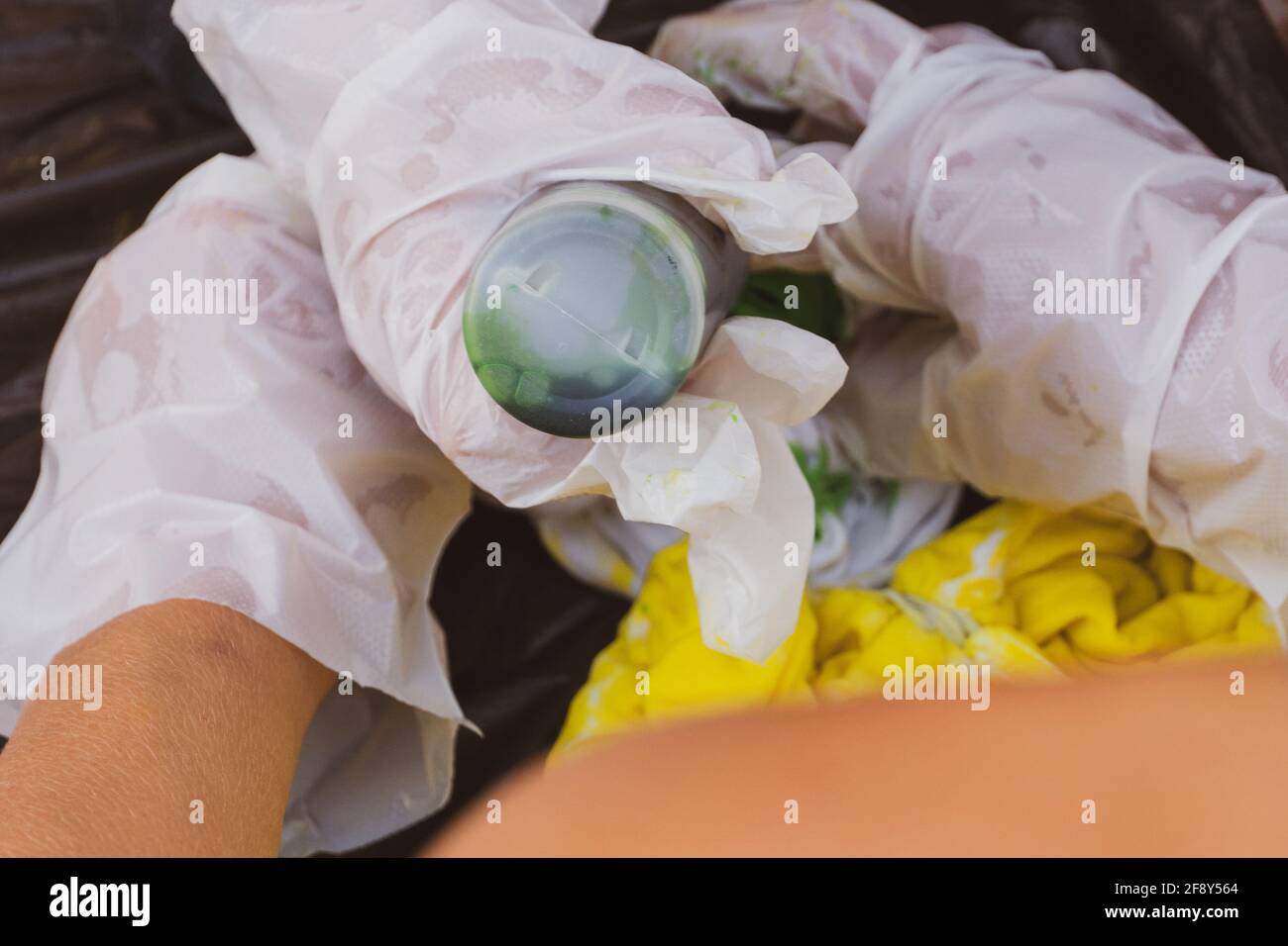 Lancette per bambini tie dye mani mettendo tinta giallo e verde su una camicia bianca per concetti artistici creativi. Foto Stock