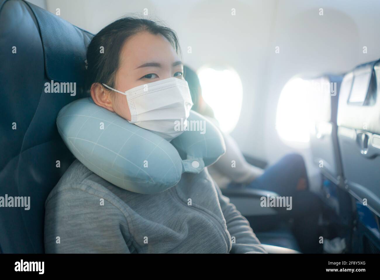 Donna turistica asiatica che vola in tempi di covid19 - giovane Felice ed eccitata ragazza giapponese in maschera di faccia seduta sopra cabina per aereo pronta per il volo Foto Stock
