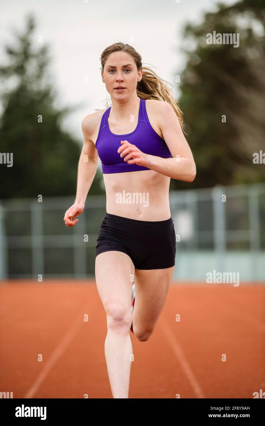Giovane donna che corre in pista Foto Stock