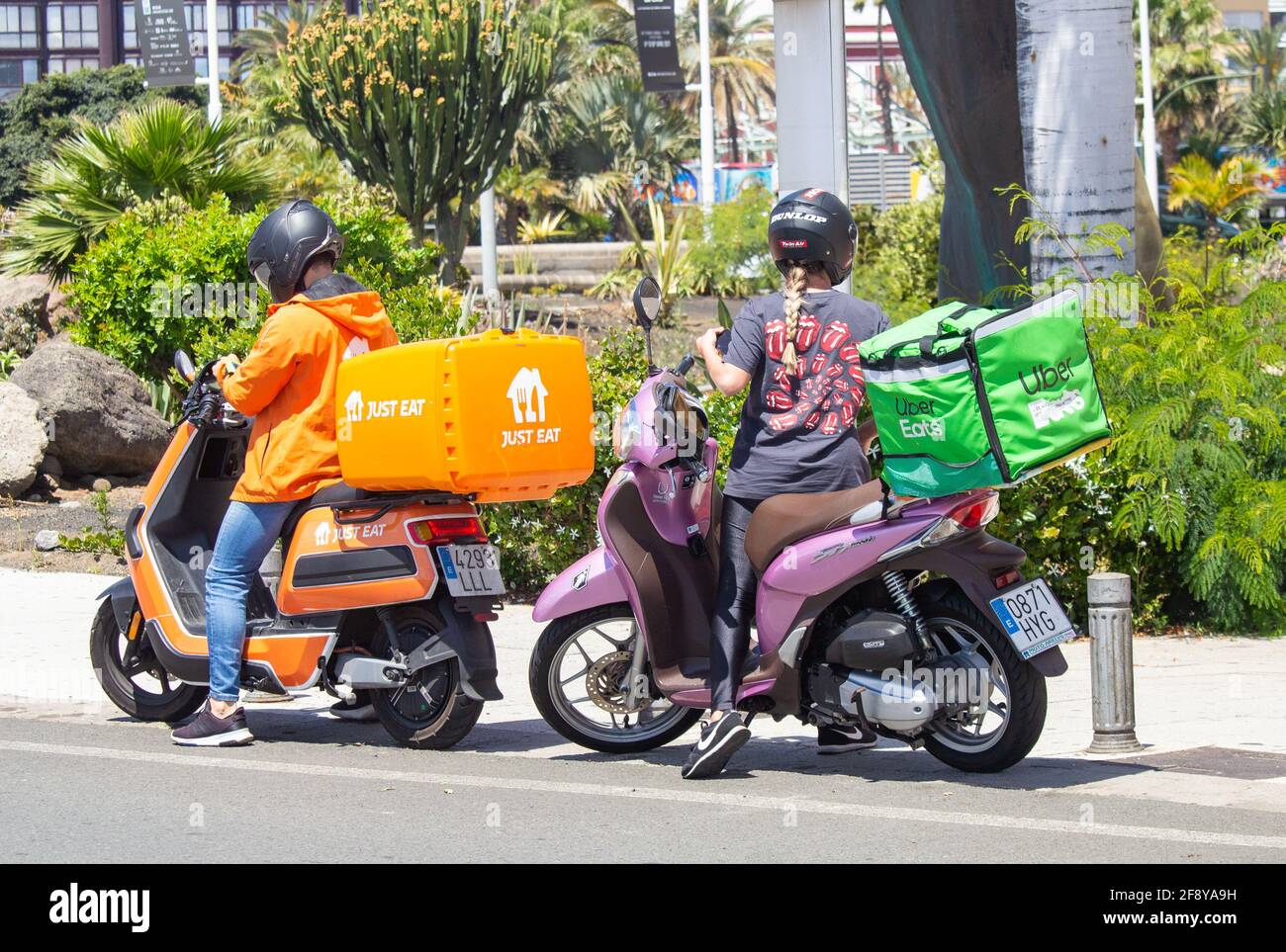 Basta mangiare corriere e donna Uber consegna rider. Basta mangiare il pilota in divisa arancione e basta mangiare scooter / moto in Spagna. Foto Stock