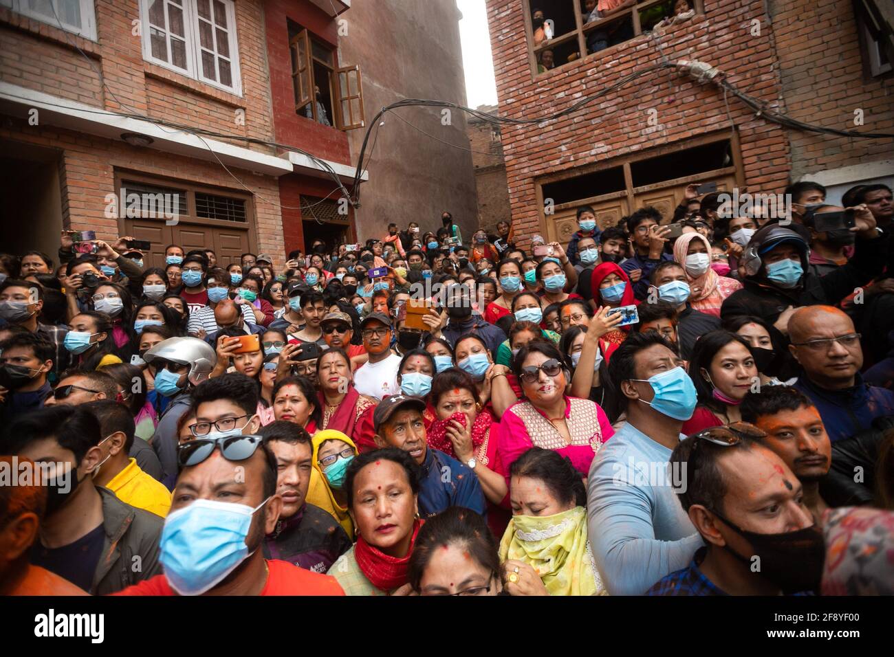 Bhaktapur, Nepal. 15 Aprile 2021. La gente osserva come i devoti celebrano il festival della polvere di vermillion di Jatra. I rivelatori portarono carri degli dei e delle dea indù e si gettarono vermilioni di polvere l'uno sull'altro come parte delle celebrazioni che iniziarono il nuovo anno nepalese. Credit: SOPA Images Limited/Alamy Live News Foto Stock