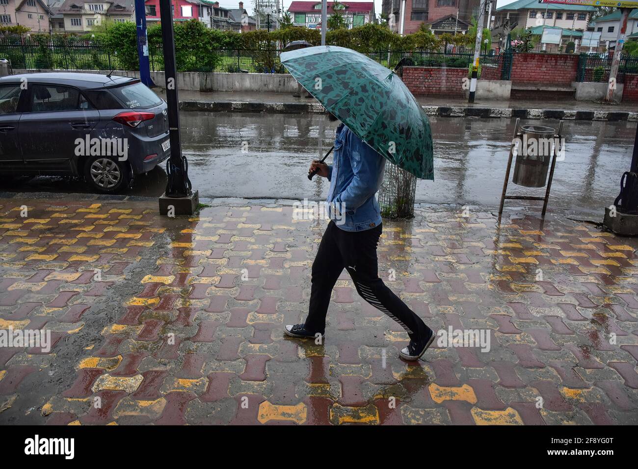 Srinagar, India. 15 Aprile 2021. Un uomo tiene un ombrello mentre cammina lungo una strada durante le precipitazioni a Srinagar. Credit: SOPA Images Limited/Alamy Live News Foto Stock