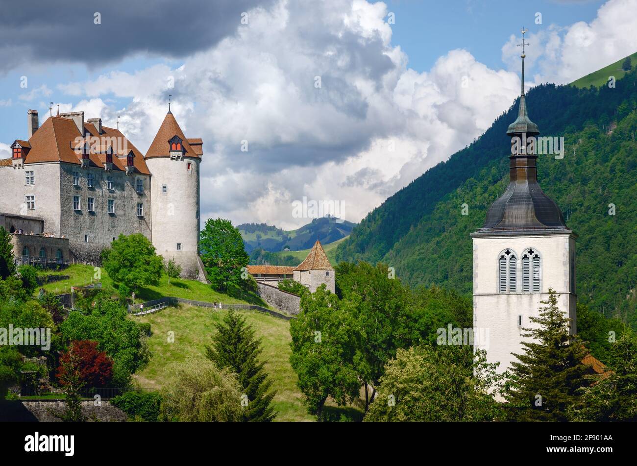 Vista esterna del villaggio di Gruyeres, famosa città casearia della svizzera, con il suo castello medievale e il campanile in cima alle colline su Foto Stock