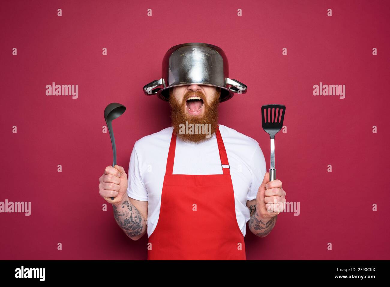 Uomo chef è pronto a combattere in cucina. Burgundies sfondo Foto Stock