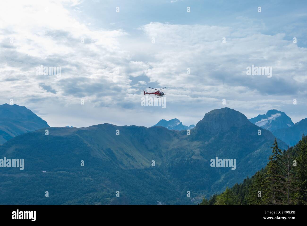 Auris, Isere, Francia - 22 agosto 2019: Vista panoramica del paesaggio alpino e elicottero sotto le nuvole nelle Alpi del Nord, dipartimento dell'Isère, Francia Foto Stock