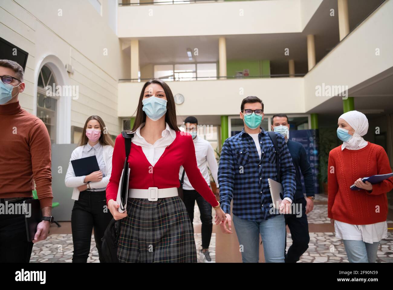 gruppo di studenti all'università che cammina e indossa la maschera facciale Foto Stock