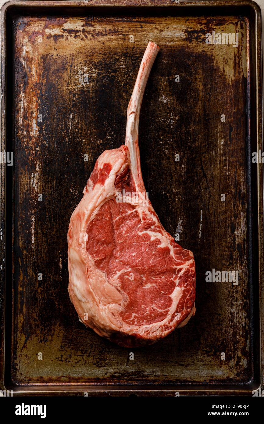 Carne fresca cruda Tomahawk bistecca sull'osso su sfondo scuro Foto Stock