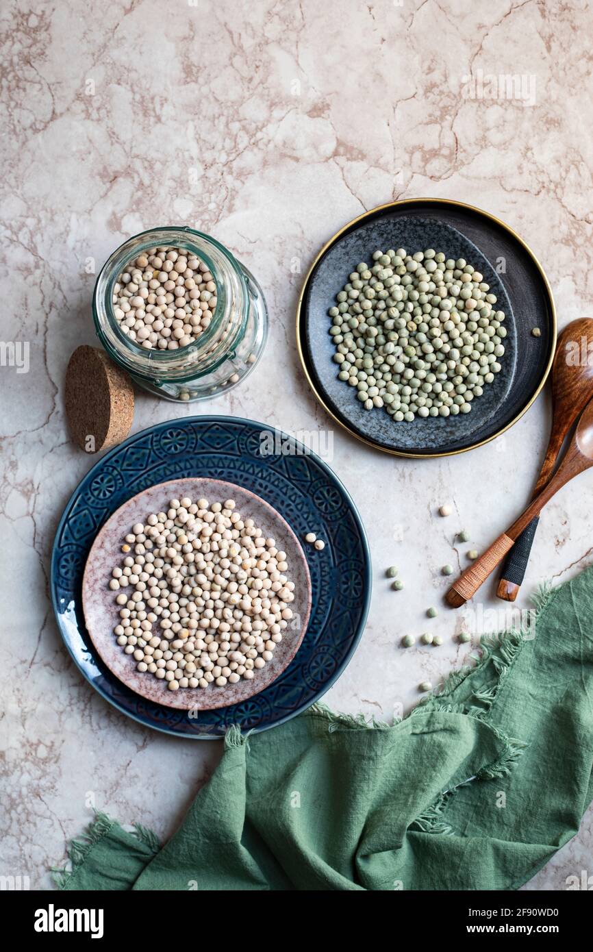 Piselli gialli e verdi su un piatto e un bicchiere vasetto Foto Stock