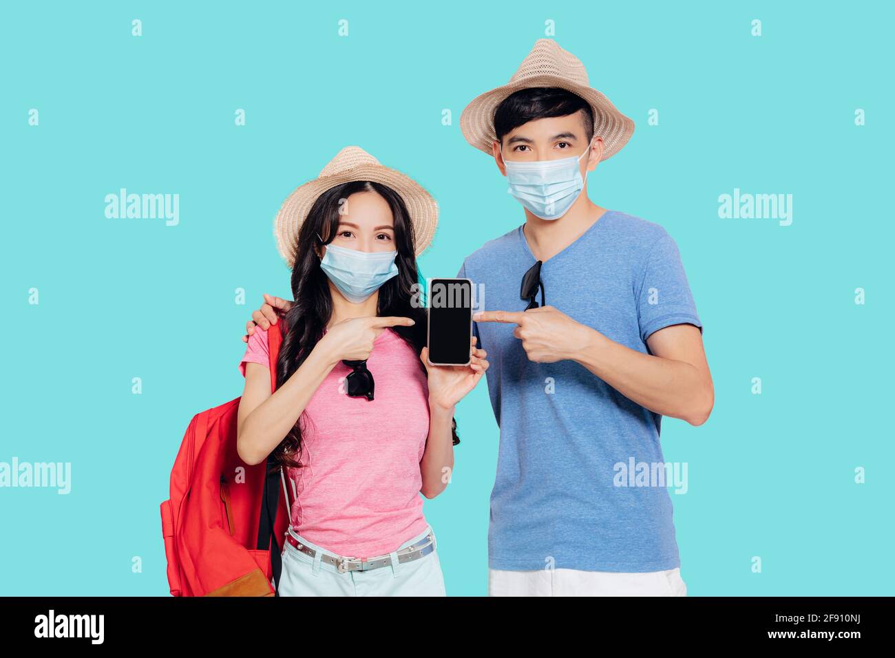 Giovane coppia in maschere di faccia e mostrando telefono cellulare per viaggi in estate Foto Stock