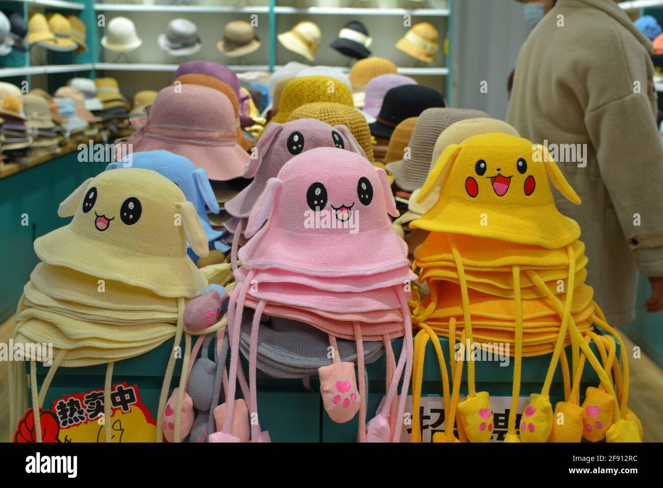Cappelli felici in vendita in un negozio. I volti luminosi e colorati creano un'immagine accattivante. Foto Stock