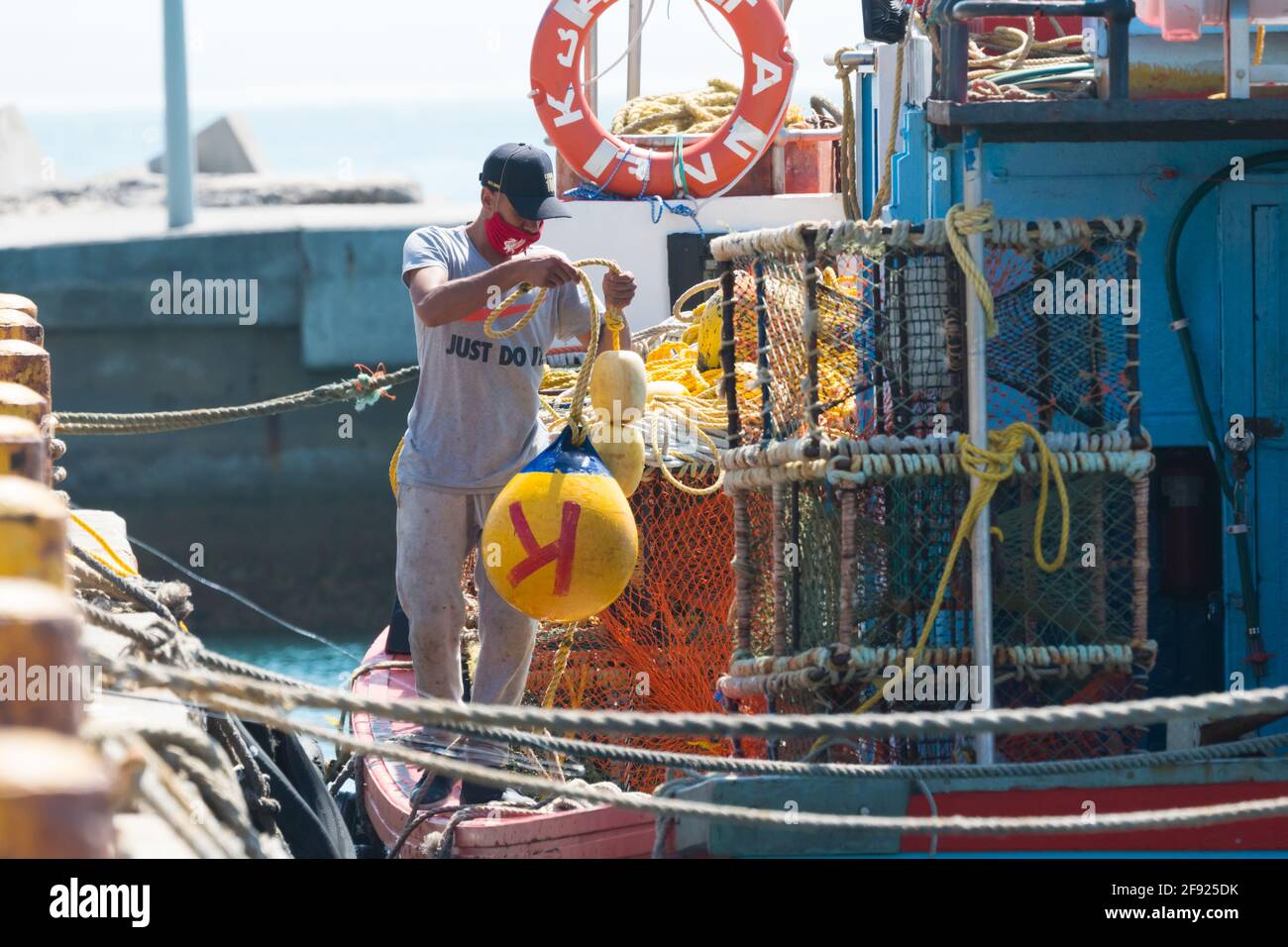 Pescatore sudafricano che lavora su una barca da pesca a Kalk Bay Harbor concetto di industria della pesca Sud Africa Foto Stock