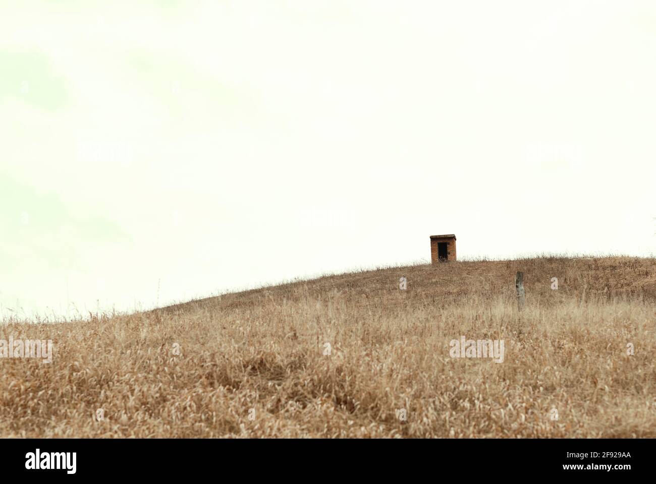 una solitaria capanna sorge in montagna, serve come rifugio per pastori in cattive condizioni atmosferiche. paesaggio minimalistico. Grigio in natura. Cielo d'autunno. Foto Stock