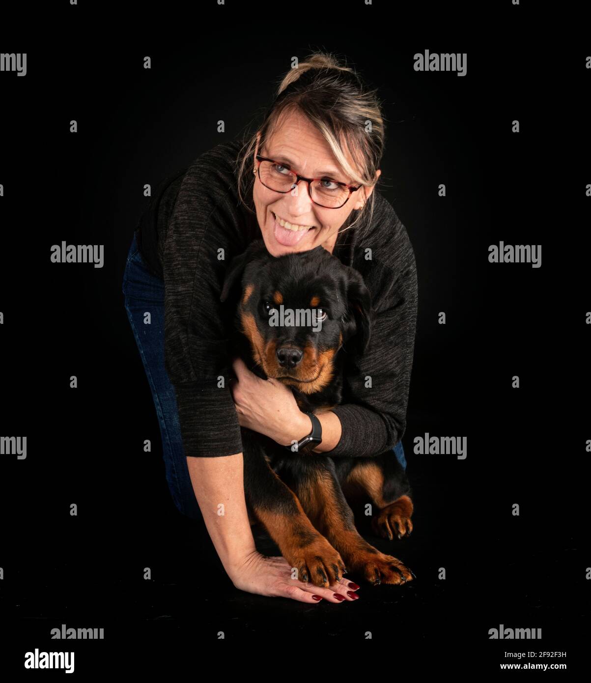 puebred rottweiler e donna di fronte a sfondo nero Foto Stock