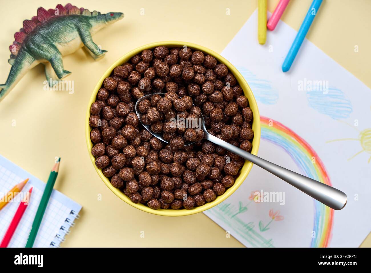 Top Visualizza cornflakes al cioccolato in una ciotola sullo sfondo di disegni e giocattoli per bambini`s. Foto Stock